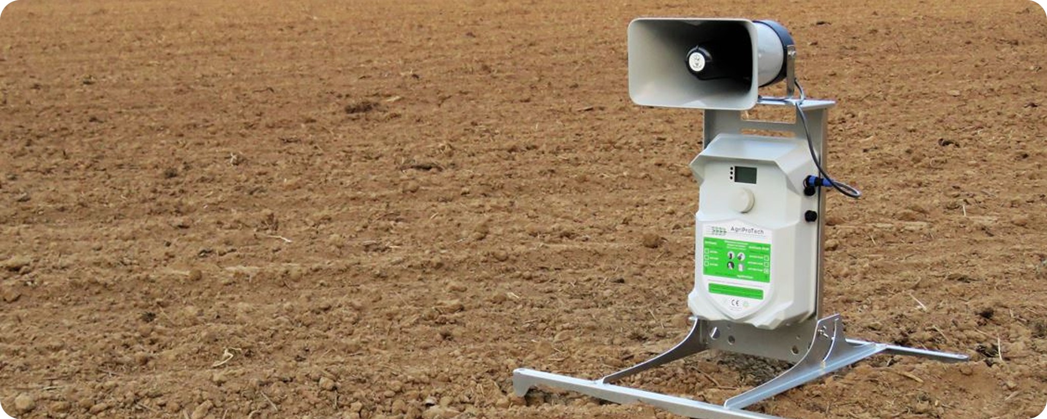 sonore Un dispositif anti-oiseaux doté d'un haut-parleur est placé sur le sol nu d'un champ, susceptible de protéger les cultures en émettant des sons pour dissuader les oiseaux.